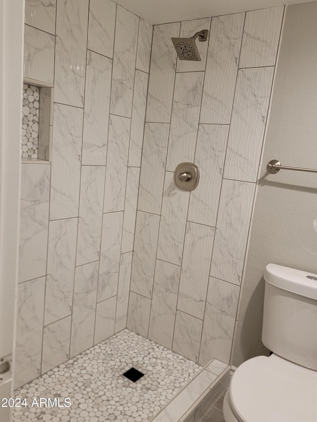 bathroom featuring a tile shower and toilet