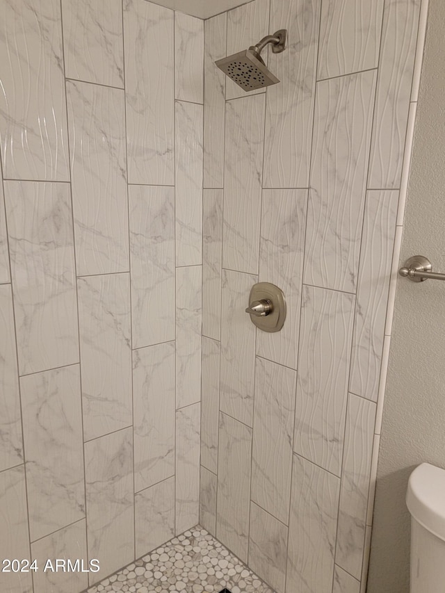 bathroom featuring toilet and tiled shower