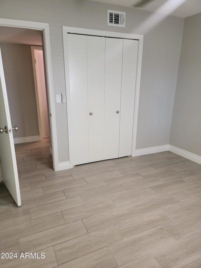 unfurnished bedroom with light hardwood / wood-style floors and a closet