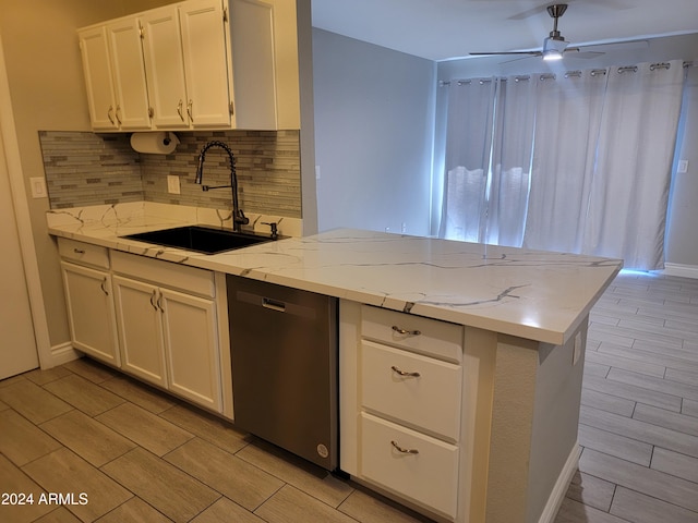 kitchen featuring white cabinetry, sink, stainless steel dishwasher, and light stone counters