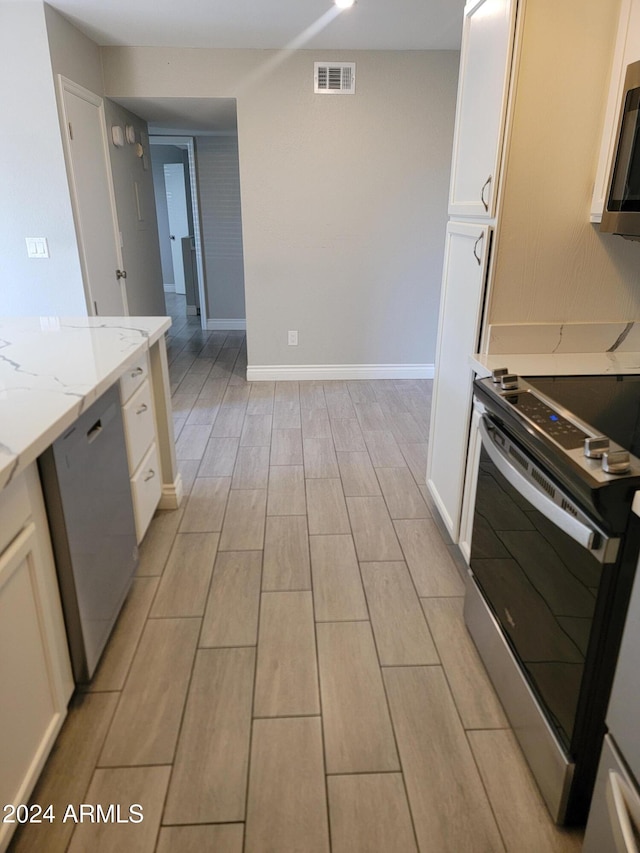 kitchen featuring white cabinets, light stone counters, and appliances with stainless steel finishes