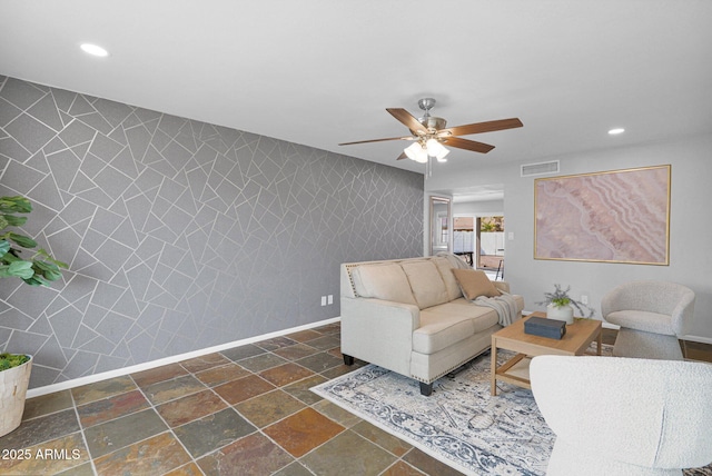 living room featuring visible vents, stone tile floors, baseboards, and wallpapered walls