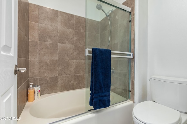 bathroom featuring toilet and shower / bath combination with glass door