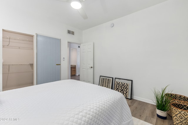 bedroom with ceiling fan, a closet, light hardwood / wood-style flooring, and a spacious closet