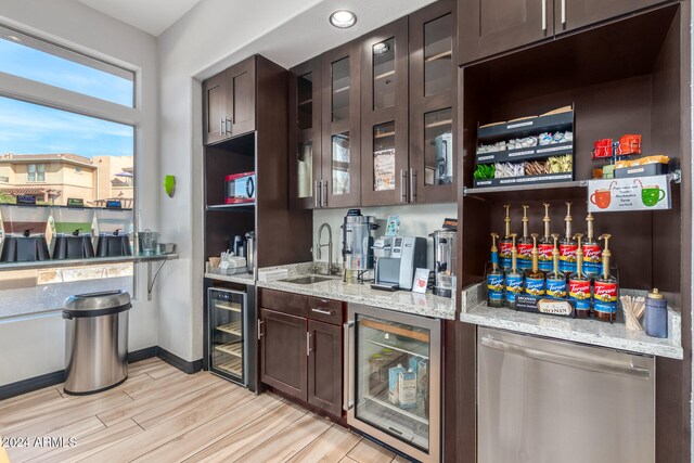 bar with light stone countertops, beverage cooler, sink, and light hardwood / wood-style floors