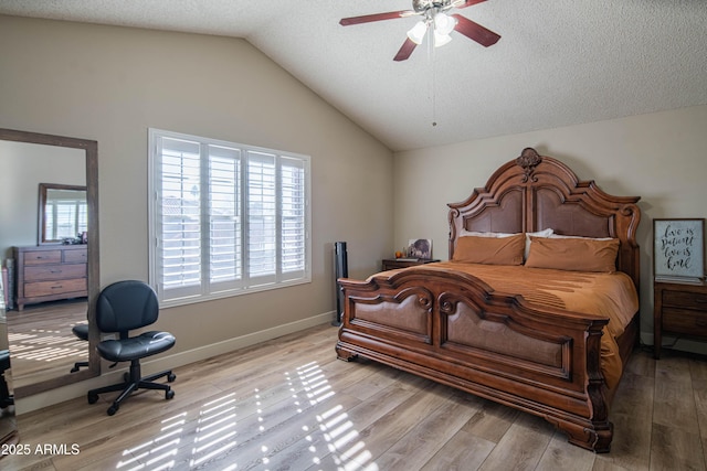 bedroom with ceiling fan, lofted ceiling, light hardwood / wood-style floors, and a textured ceiling