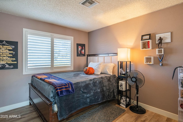 bedroom featuring hardwood / wood-style floors and a textured ceiling