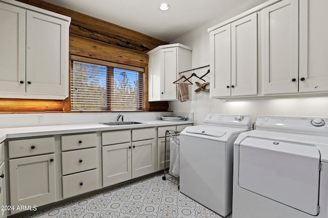 clothes washing area with washer and dryer, light tile floors, cabinets, and sink