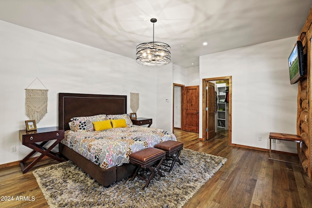 bedroom with dark hardwood / wood-style floors, an inviting chandelier, a spacious closet, and a closet