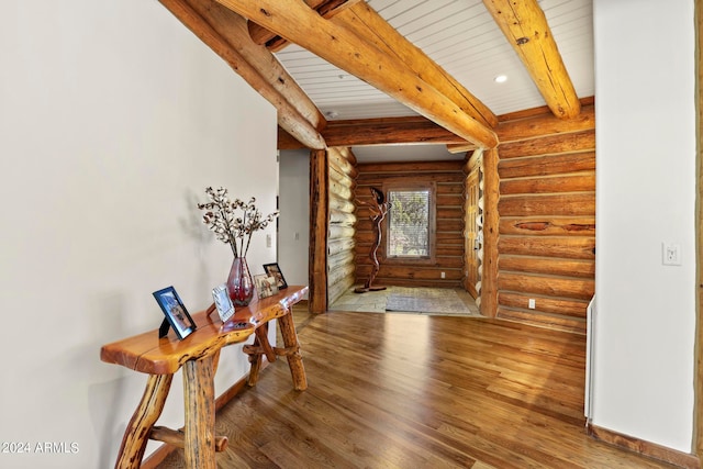 foyer entrance with rustic walls, beam ceiling, and dark hardwood / wood-style floors