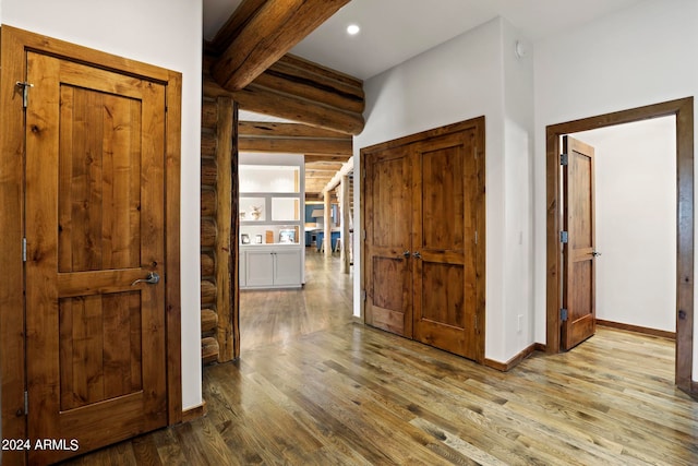 corridor with light hardwood / wood-style floors and beamed ceiling