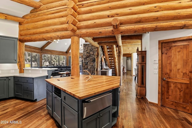 kitchen with vaulted ceiling with beams, rustic walls, dark wood-type flooring, and gray cabinetry