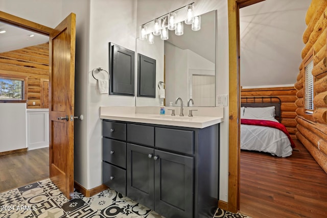 bathroom with hardwood / wood-style floors, rustic walls, wood walls, vaulted ceiling, and vanity