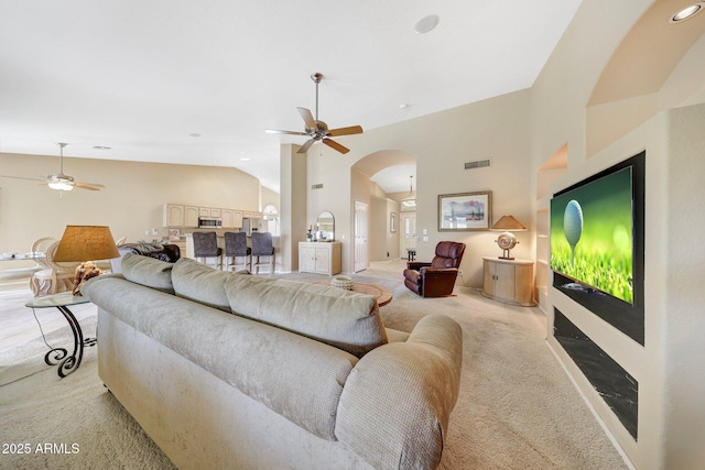 living room with arched walkways, light carpet, a ceiling fan, and visible vents