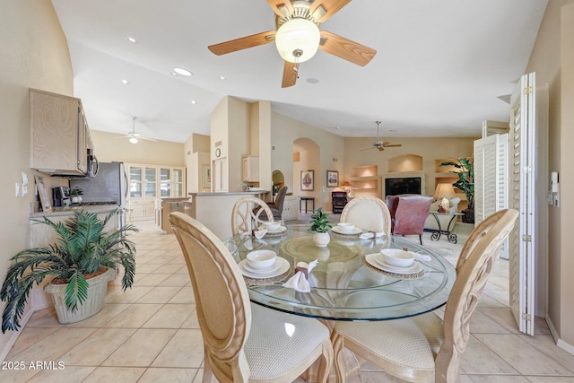 dining room featuring a ceiling fan, arched walkways, and light tile patterned floors