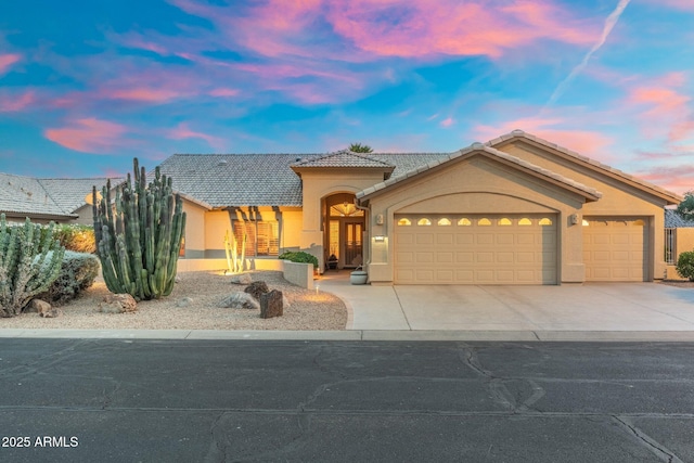 view of front of house featuring an attached garage, stucco siding, a tile roof, and concrete driveway