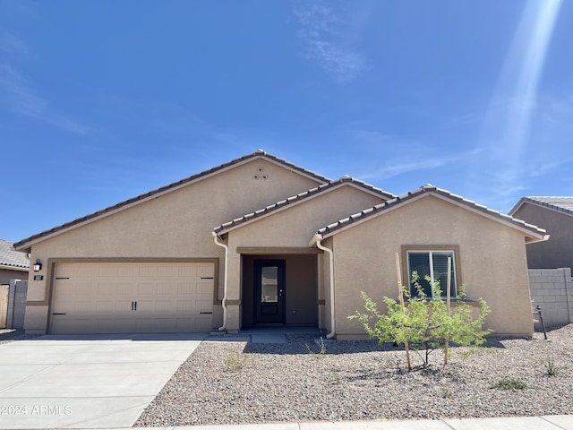 view of front facade featuring a garage, concrete driveway, a tile roof, and stucco siding