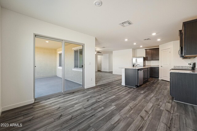 kitchen featuring visible vents, dark wood finished floors, open floor plan, a kitchen island with sink, and light countertops