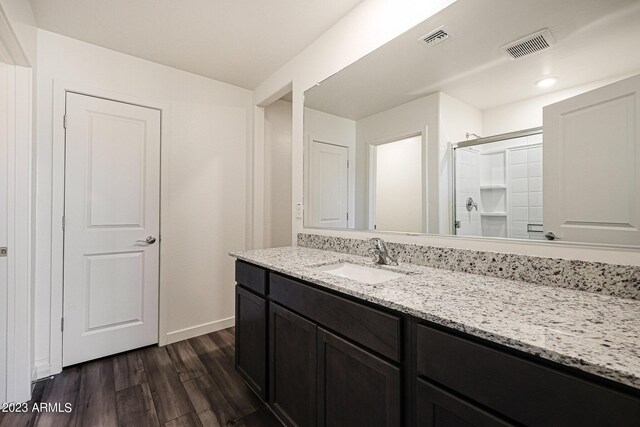 full bathroom with a stall shower, visible vents, vanity, and wood finished floors