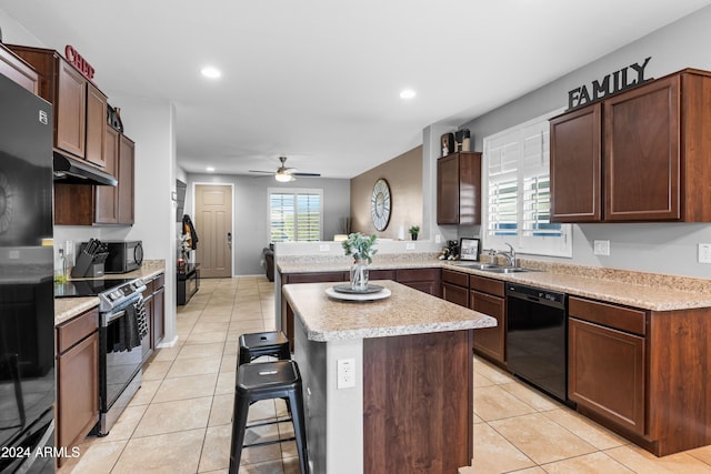 kitchen featuring kitchen peninsula, a breakfast bar, sink, black appliances, and light tile patterned flooring