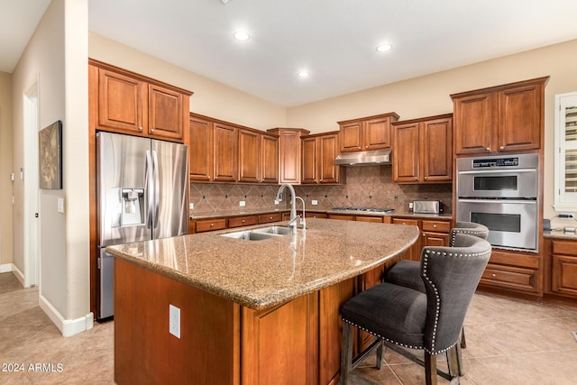 kitchen featuring a sink, appliances with stainless steel finishes, brown cabinetry, and under cabinet range hood