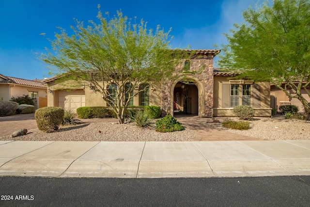 view of front of house featuring a tile roof, stucco siding, decorative driveway, stone siding, and an attached garage