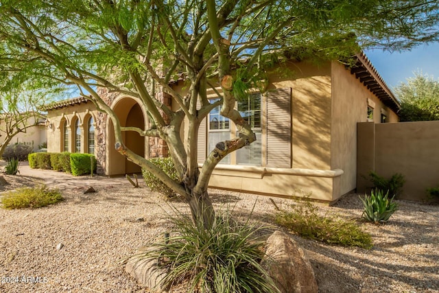 view of side of home with fence and stucco siding