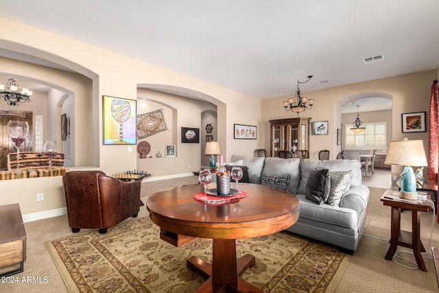 living area featuring baseboards, arched walkways, visible vents, and a chandelier