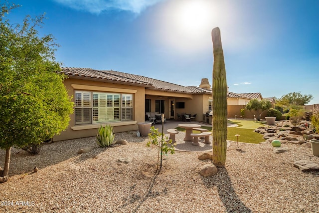 rear view of house featuring a patio area, stucco siding, a tiled roof, and a chimney