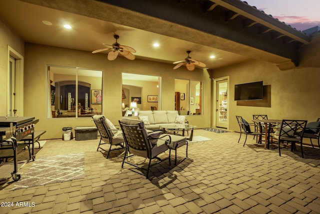 patio terrace at dusk featuring an outdoor hangout area, outdoor dining space, and a ceiling fan