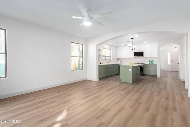 kitchen with pendant lighting, green cabinets, appliances with stainless steel finishes, white cabinets, and a kitchen island