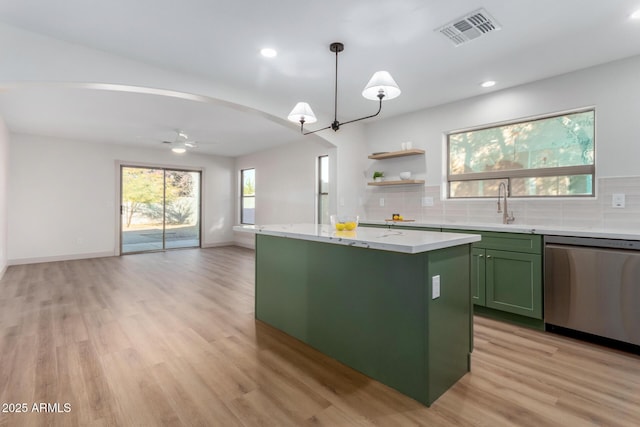 kitchen with stainless steel dishwasher, light hardwood / wood-style flooring, hanging light fixtures, green cabinetry, and a kitchen island