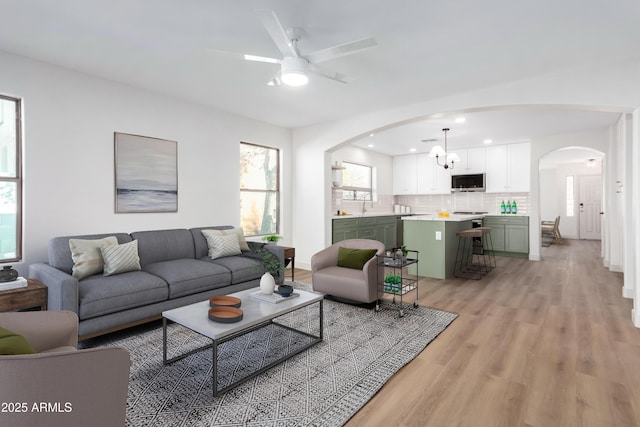 living room with ceiling fan, sink, and light wood-type flooring