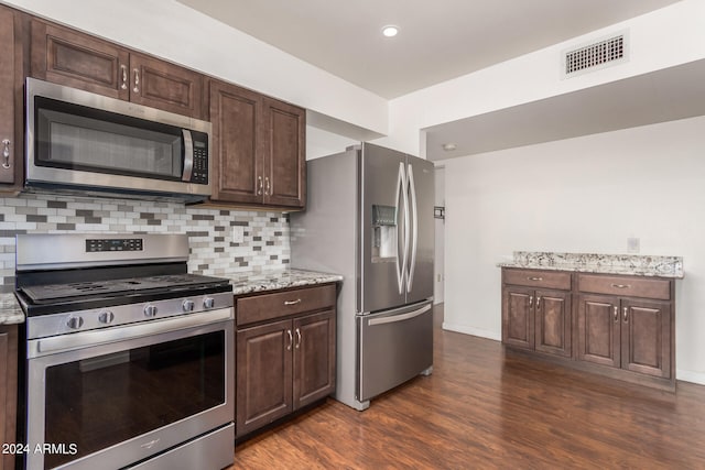 kitchen featuring light stone countertops, stainless steel appliances, dark hardwood / wood-style flooring, and tasteful backsplash