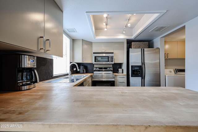 6533 N 10th Pl, Phoenix, AZ 85014 - kitchen with stainless steel appliances, a raised ceiling, independent washer and dryer, rail lighting, and a sink