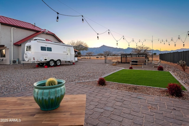 patio terrace at dusk with a mountain view and a yard