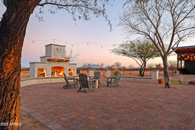 patio terrace at dusk with an outdoor brick fireplace