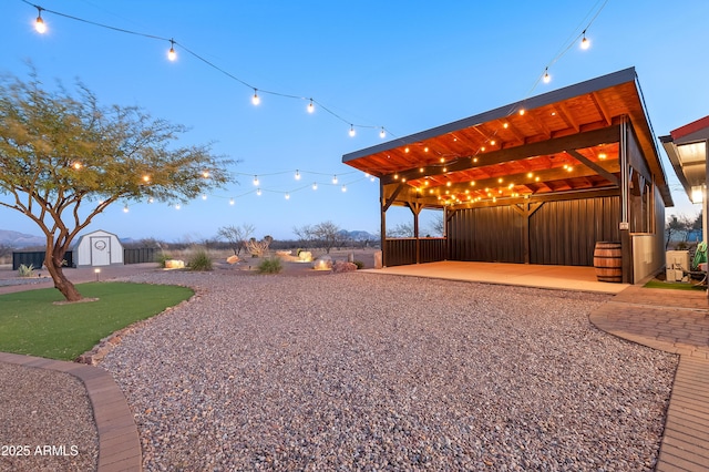 yard at dusk featuring a patio area and a storage unit