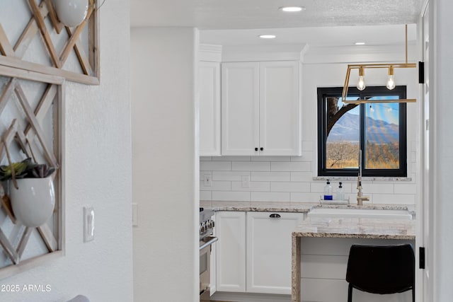 kitchen featuring white cabinetry, sink, light stone counters, and decorative backsplash