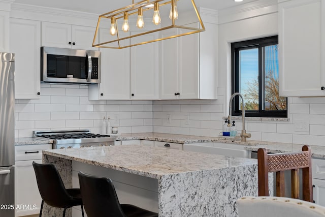 kitchen with a breakfast bar, sink, decorative light fixtures, stainless steel appliances, and white cabinets