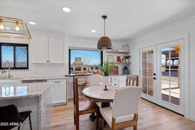 dining room with sink, crown molding, light hardwood / wood-style flooring, and french doors