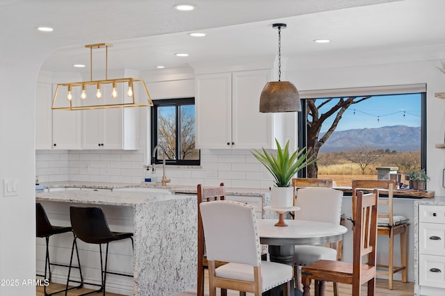 kitchen featuring a mountain view, pendant lighting, white cabinets, and light stone counters