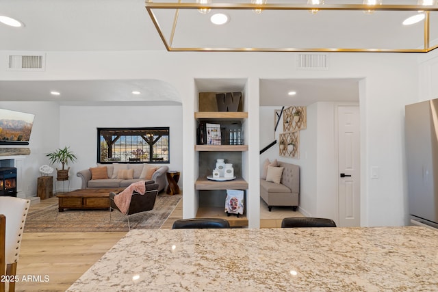 interior space with light stone countertops, stainless steel refrigerator, and light wood-type flooring