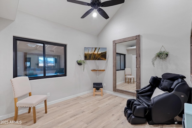 living area with ceiling fan, high vaulted ceiling, and light hardwood / wood-style floors