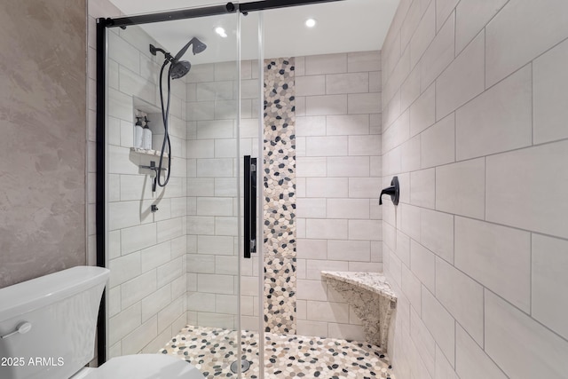 bathroom featuring a shower with door and toilet