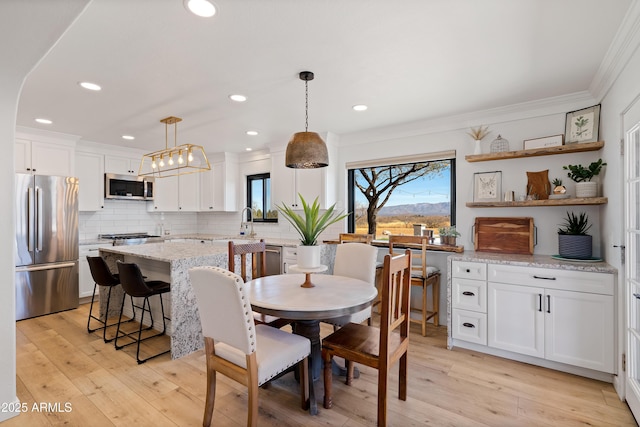 dining space with sink, crown molding, and light hardwood / wood-style floors