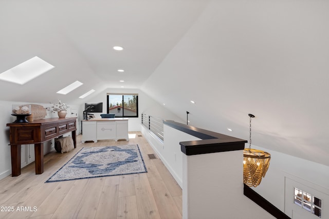 interior space with a notable chandelier, light hardwood / wood-style flooring, and lofted ceiling with skylight