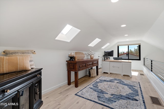 home office featuring lofted ceiling with skylight and light wood-type flooring