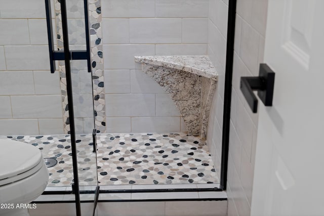 bathroom with tiled shower and toilet