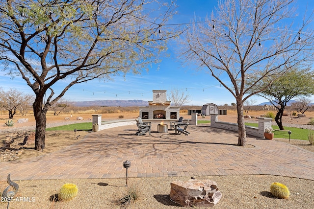 exterior space featuring a shed, a mountain view, and an outdoor stone fireplace